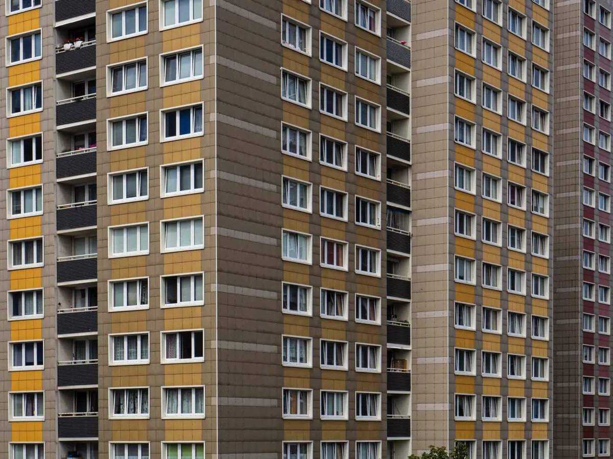 Fasáda panelového domu s mnoha balkony a barevnými obkladovými panely